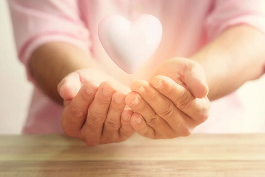 Frau faltet Hände zusammen, darüber schwebt ein rosa Herz zum Thema Kaffee und Cholesterin